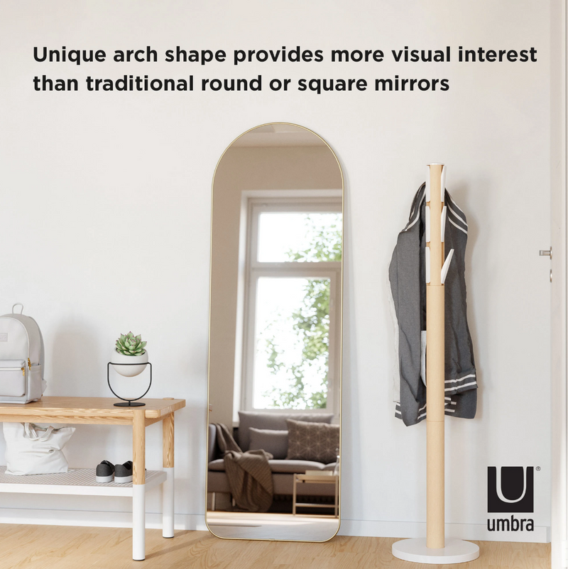 The Umbra HUBBA ARCHED LEANING MIRROR - BRASS with a unique arch shape and metallic finish rim provides more visual appeal than traditional round or square mirrors.