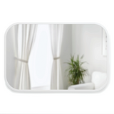 The Umbra range features a Hub Rectangle Mirror - White, gracefully placed in a room adorned with curtains and a plant.