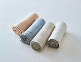 A set of four Nawrap Organic Fitness Towels on a white surface showcasing their water absorbency and breathability.