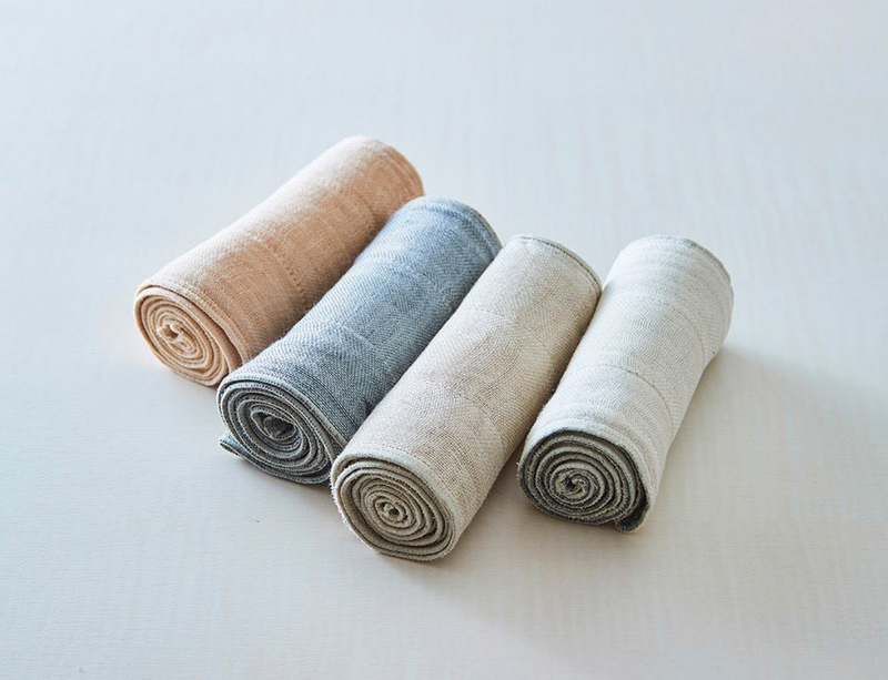A set of four Nawrap Organic Fitness Towels on a white surface showcasing their water absorbency and breathability.