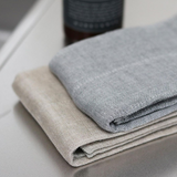 A set of Nawrap Organic Fitness Towels on a table with a water absorbency bottle on top.