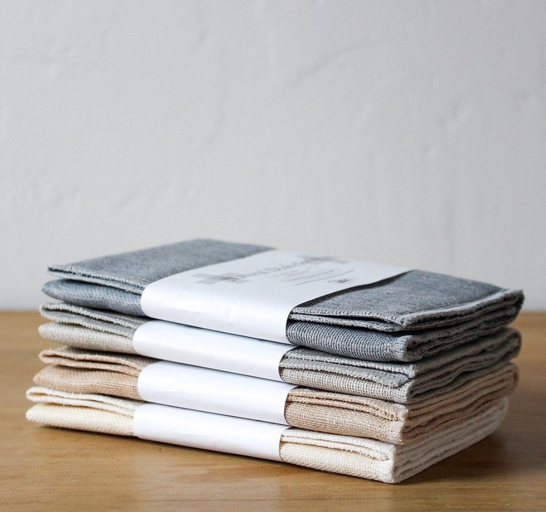 Stack of four packaged Nawrap Natural Dishcloths on a timber bench
