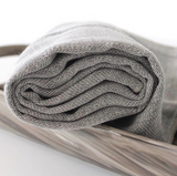A gray ORGANIC FITNESS TOWEL, known for its superb water absorbency, is sitting in a wooden tray.