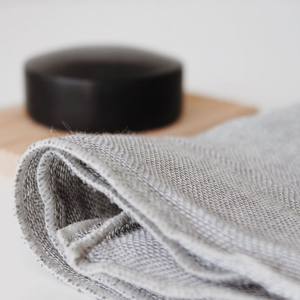 A Nawrap Organic Face Towel with a black soap on top of it.