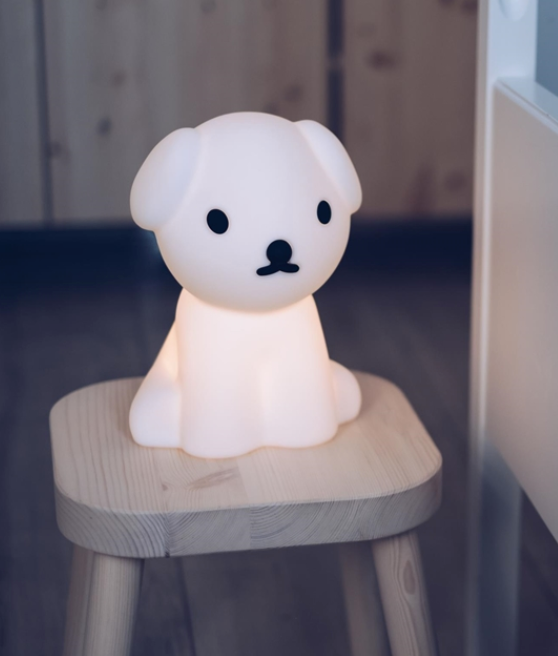 Snuffy First Light lamp, a glowing white puppy, sitting on a timber stool