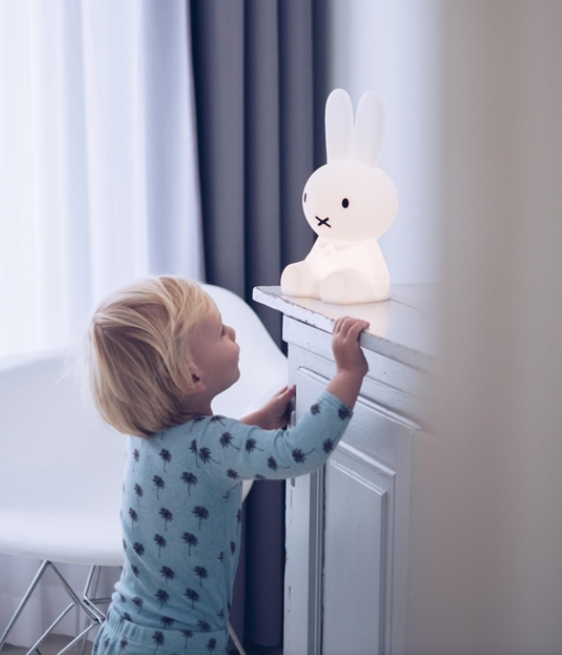 Child reaching up to the Mr Maria Miffy First Light on a windowsill shelf