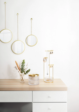 A customizable white dresser with three gold DIMA ROUND mirrors from Umbra and a vase.