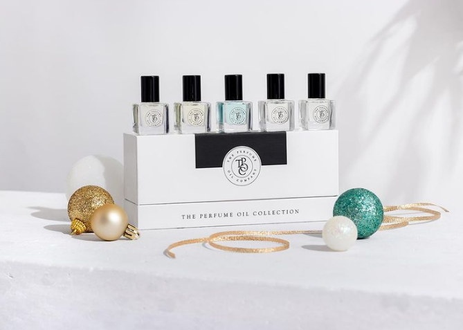 Perfume oil roll-on gift box on a white table with gold and green baubles