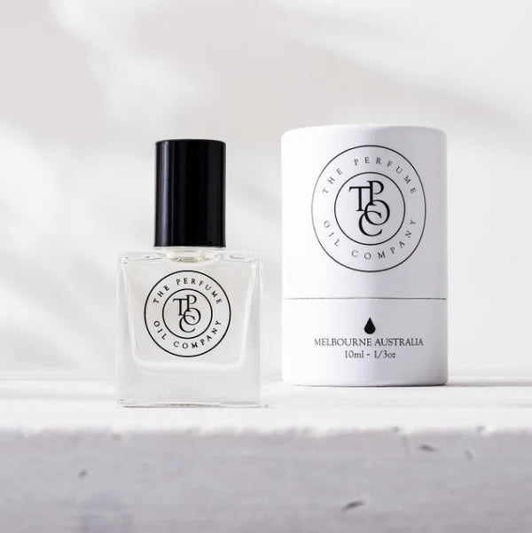 Perfume oil roll-on bottle beside its white box on a pale stone surface