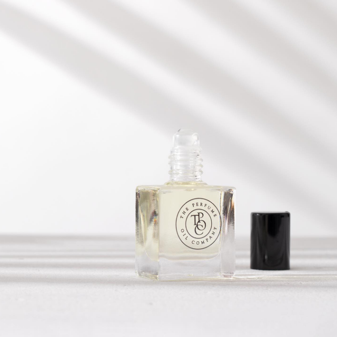 Perfume oil bottle with its cap removed in soft light and shadow