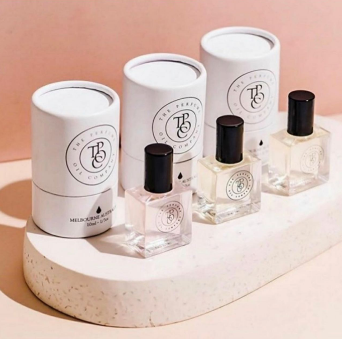 Three bottles of SANTAL fragrance on a pink pedestal, perfect for gifting and showcasing the beauty of The Perfume Oil Company's creation inspired by Santal 33 by Le Labo.