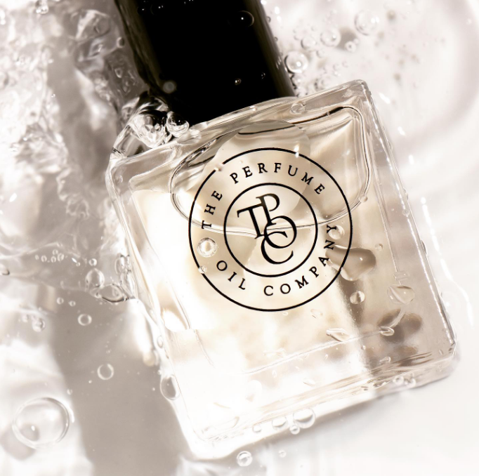 A designer bottle of BLONDE perfume oil sitting on top of water, inspired by Bloom (Gucci).
