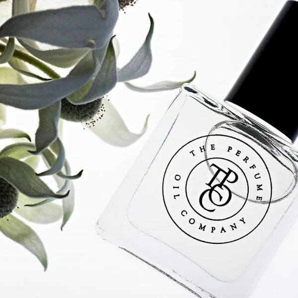 Close view of a perfume oil bottle label beside grey-green leaves