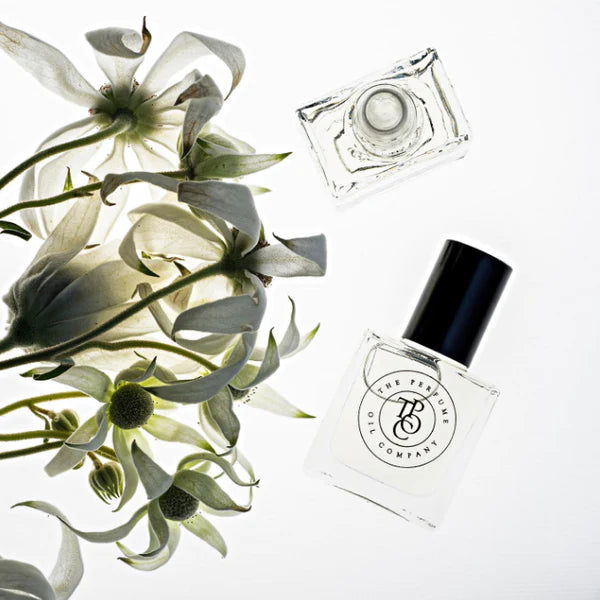 Perfume oil bottles laid among white flowers and grey-green foliage
