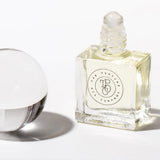 A bottle of CALYPSO perfume inspired by Mango Skin (Vilhelm Parfumerie), next to a glass ball, by The Perfume Oil Company.