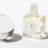 A bottle of GHOST fragrance by The Perfume Oil Company next to a glass ball.