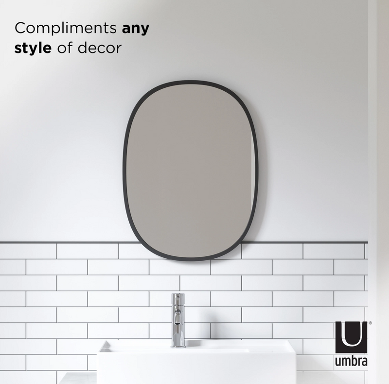 A bathroom with a white sink and the Hub Mirror Oval - Black featuring a rubber rim by Umbra.