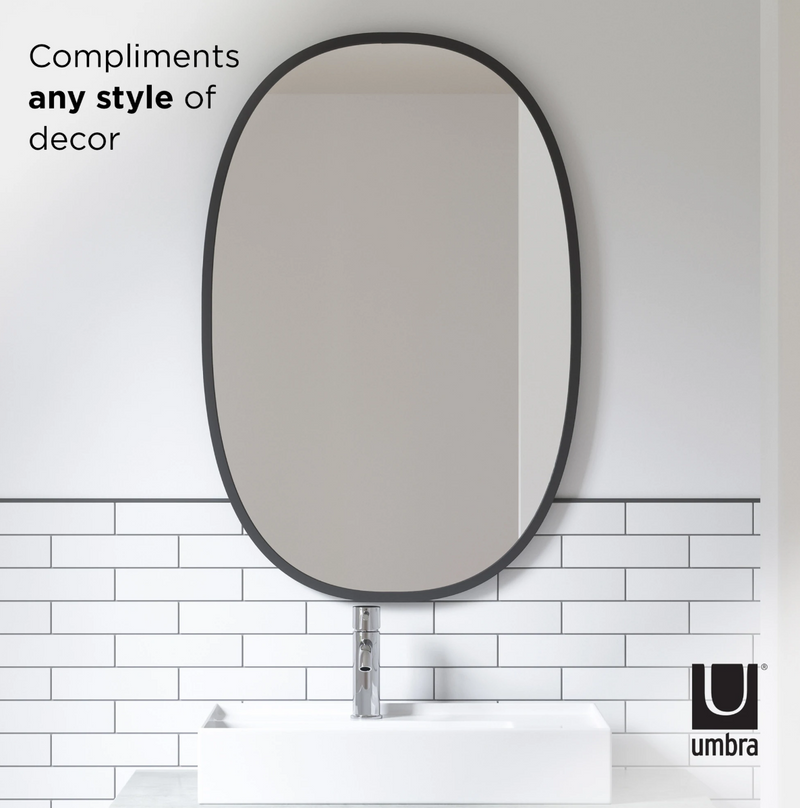 A bathroom with a white sink, mirror, and the sleek Umbra Hub Mirror Oval - Black featuring a stylish rubber rim.
