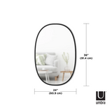 The Hub Mirror Oval - Black by Umbra, a black oval mirror with a sleek rubber rim, beautifully enhances any living room.