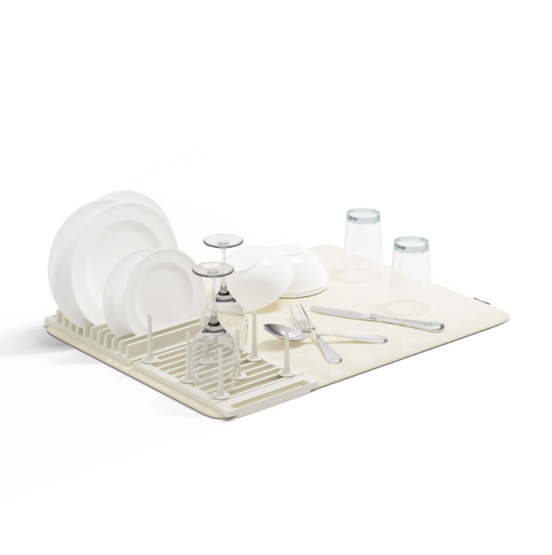 An Umbra UDRY PEG DRYING RACK WITH MAT with dishes and silverware on it.