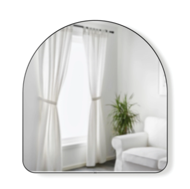 Umbra Hubba Arched Mirror in titanium leaning against a bedroom wall