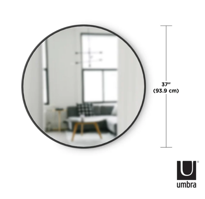 An image of a modern round mirror, also known as a Umbra HUB MIRROR - Large, in a stylish living room.