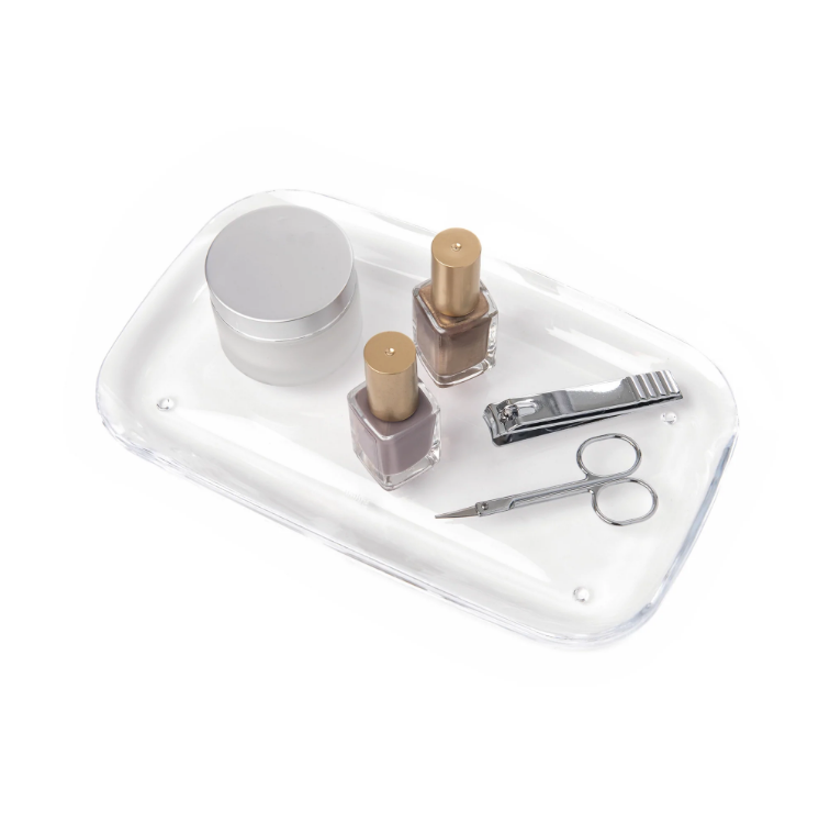 A DROPLET TRAY - CLEAR acrylic tray with nail tools and a bottle of nail polish, part of the Umbra range.