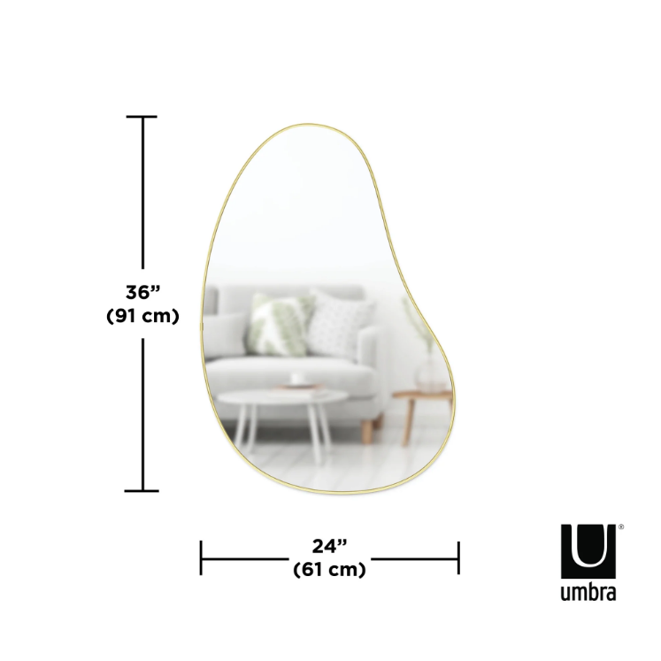 Large Umbra Hubba Pebble Mirror with a metallic frame hung in a living room.