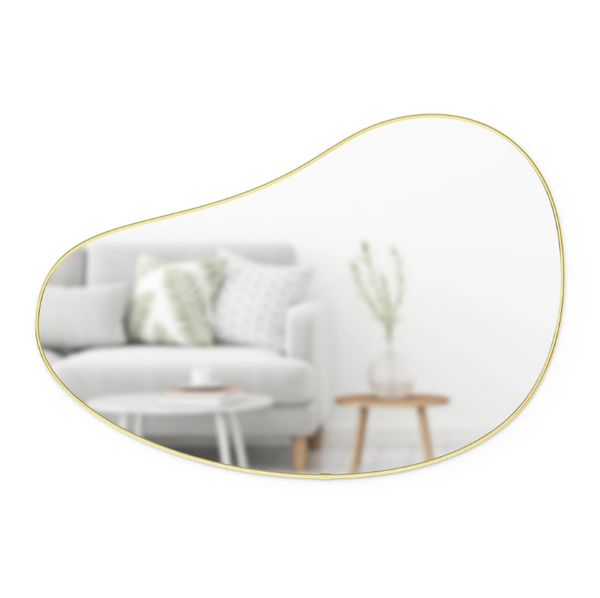 An Umbra HUBBA PEBBLE MIRROR, with an organic shape and a gold frame, featuring a metallic finish, adding elegance to the living room.