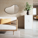 A living room with an organic-shaped couch and a HUBBA PEBBLE MIRROR with a metallic finish. (Brand: Umbra)