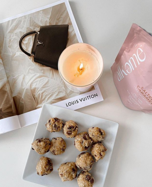 A guilt-free plate of Salted Caramel Raw Treat Mix, including Alkeme Wholefoods cookies, a bag, and a candle.