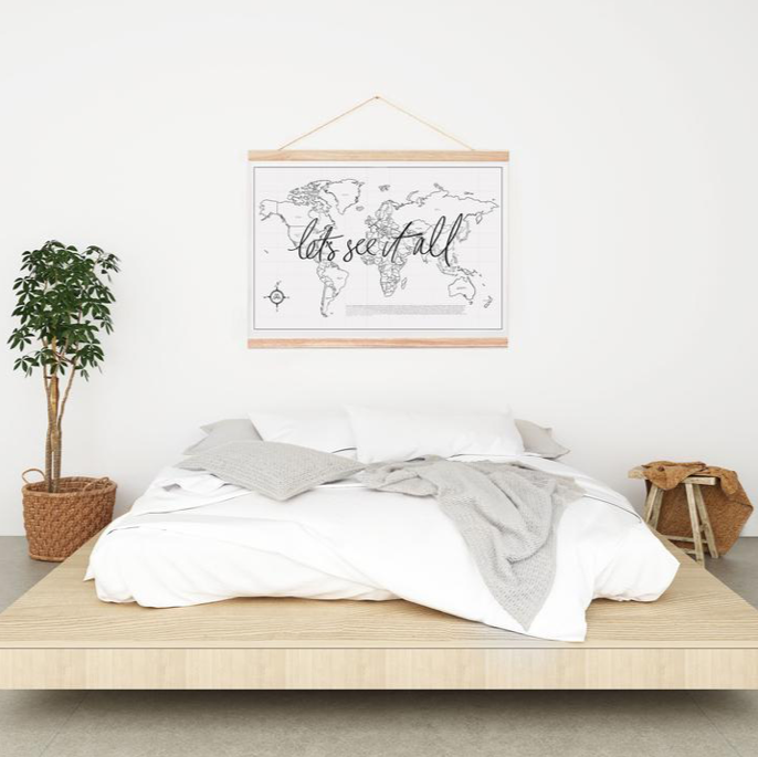 In a wanderlusting soul's bedroom, a bed sits against the wall adorned with a captivating map from AXEL & ASH's Let's See It All.