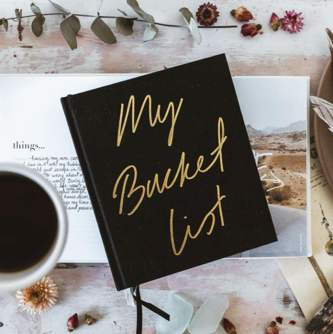Axel and Ash's My BUCKETLIST journal, accompanied by a cup of coffee.