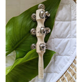 A Jaclyn and Matisse Baby Wooden Jingle Stick sitting on top of a leaf.