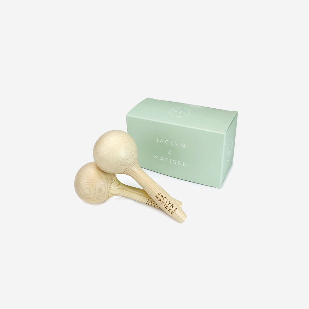 Two Jaclyn and Matisse Wooden Maraca Pairs in front of a box.