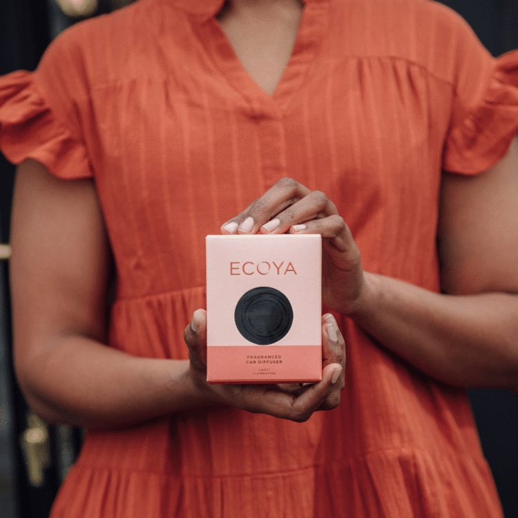 A woman showcasing a box of beautifully designed Ecoya Car Diffuser - Various Fragrances, perfect as gifts.