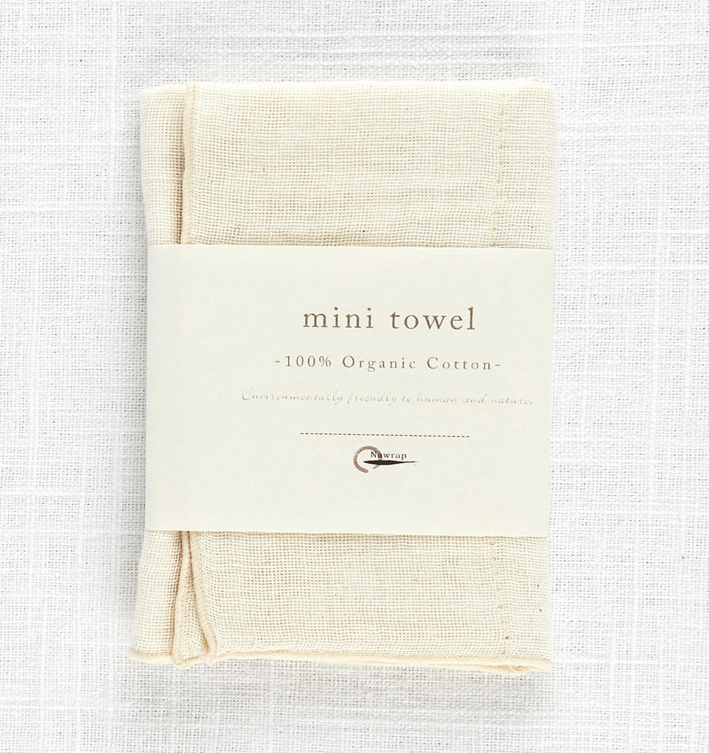 A NAWRAP ORGANIC MINI TOWEL - IVORY, perfect for sensitive skin, placed on a clean white surface.
