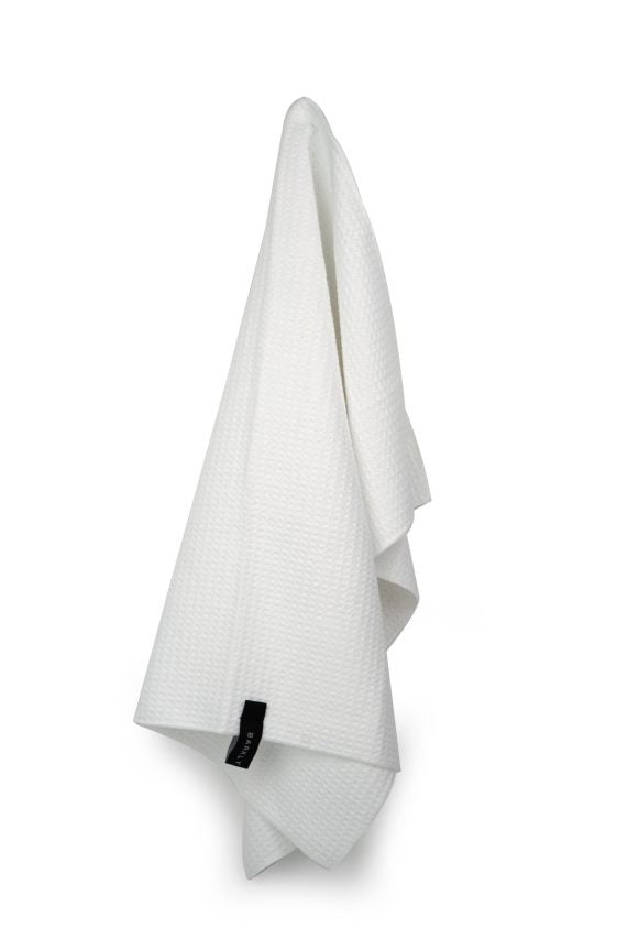 White waffle microfibre tea towel hanging by its tag against a plain background