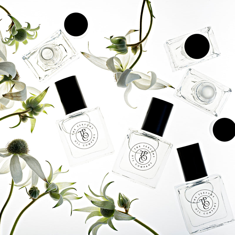 A collection of black and white bottles with flowers on them from The Perfume Oil Company, featuring SALT inspired by Wood Sage & Sea Salt from Jo Malone.