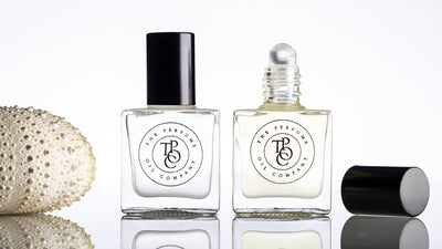 A collection of INK, inspired by Noir perfume oils showcased with a shell on a white surface by The Perfume Oil Company.