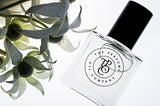 A bottle of BLEU perfume, inspired by Bleu (CC), sitting next to a flower.