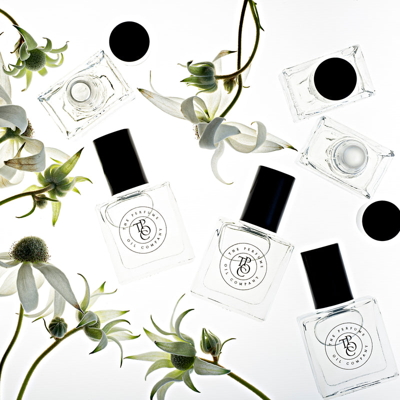 A collection of black and white ROUGE bottles with flowers on them from The Perfume Oil Company, offering exquisite perfume oils and fragrance inspired by Baccarat Rouge 540.
