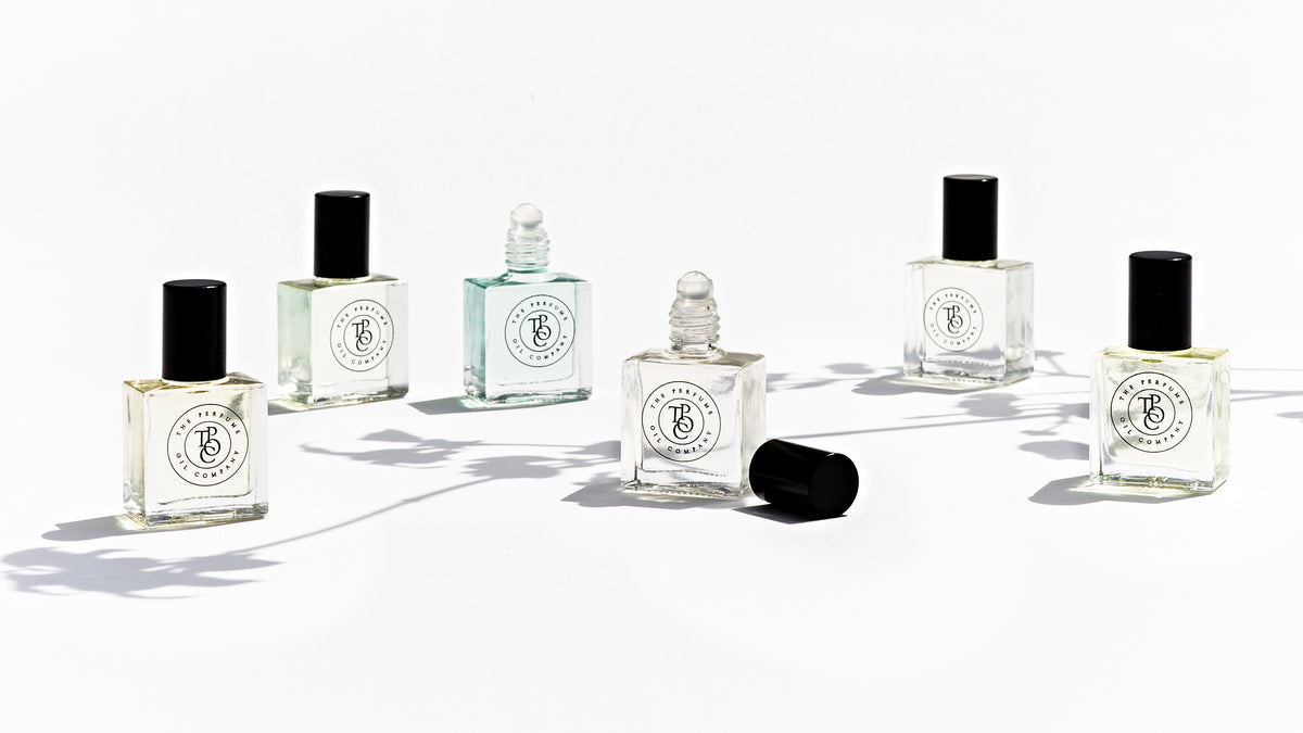 A row of perfume oil bottles in different sizes on a white surface