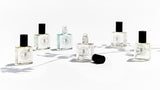 Five bottles of ROUGE perfume oils inspired by Baccarat Rouge 540, from The Perfume Oil Company, sitting on a white surface, emitting an exquisite fragrance.