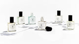 Five bottles of LUSH perfume oils inspired by Be Delicious (DKNY) sitting on a white surface, from The Perfume Oil Company.
