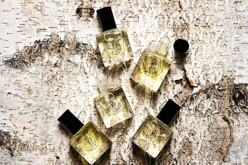 Four KASBAH roll-on perfume oils inspired by Marrakech, produced by The Perfume Oil Company, sitting on top of a piece of wood.