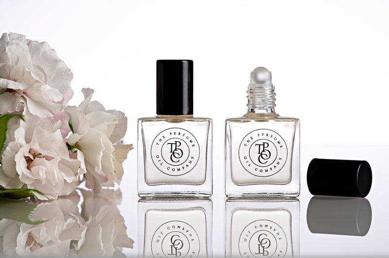 A bottle of BLEU perfume, inspired by Bleu (CC), and a bottle of flowers on a table.