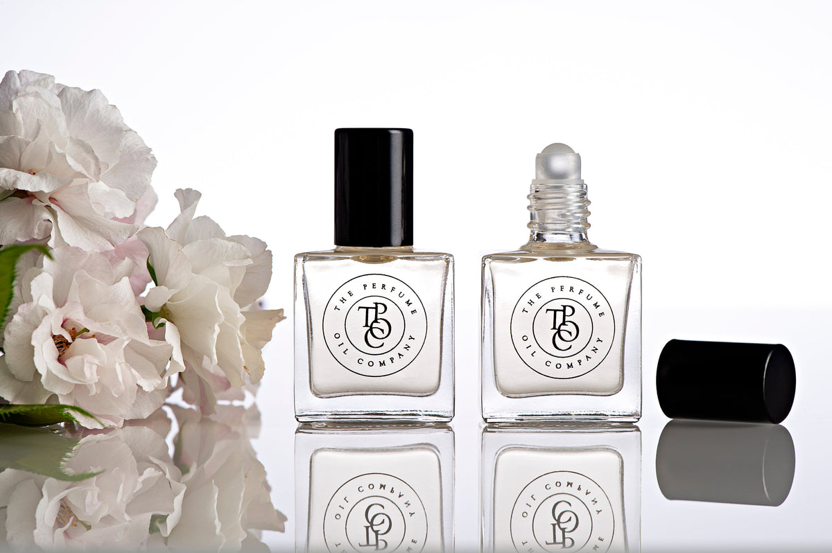 A bottle of LUSH fragrance oils inspired by Be Delicious (DKNY) from The Perfume Oil Company and a bottle of flowers on a table.