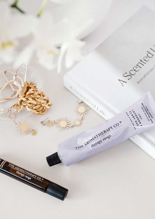 A Therapy® Pulse Point Sleep - Lavender & Chamomile from The Aromatherapy Co and a tube of lip balm on a white table.