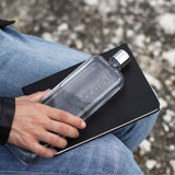 A person holding a Slim Memobottle in a notebook, tracking their daily water intake.